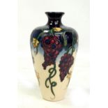 MOORCROFT; a navy and cream ground grape and vine tubeline decorated vase, impressed marks and
