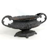 A cast iron foliate motif twin handled planter raised on oval base and four paw feet, width approx