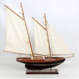 A wooden two mast model boat with cloth sails and miniaturised detail on rectangular plinth base,