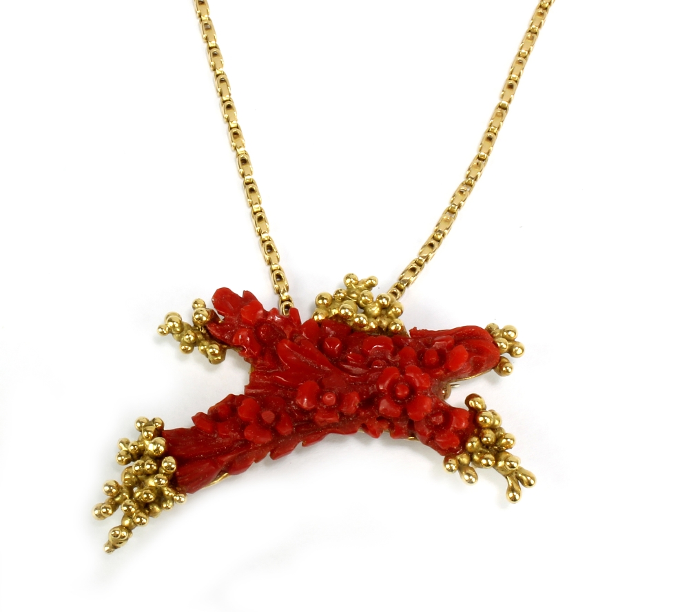 A floral decorated carved coral pendant/brooch in 18ct yellow metal mount and suspended on 18ct