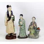 Three Chinese figures of scholars, the two smaller in porcelain and the taller earthenware, the