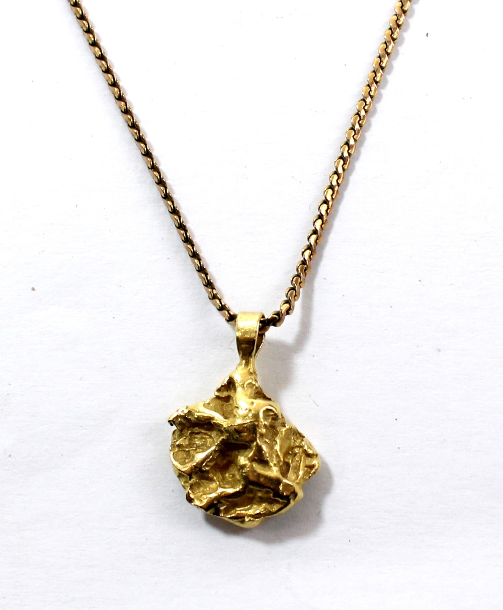 A yellow metal nugget pendant with indistinct stamp to bail suspended on a yellow metal chain
