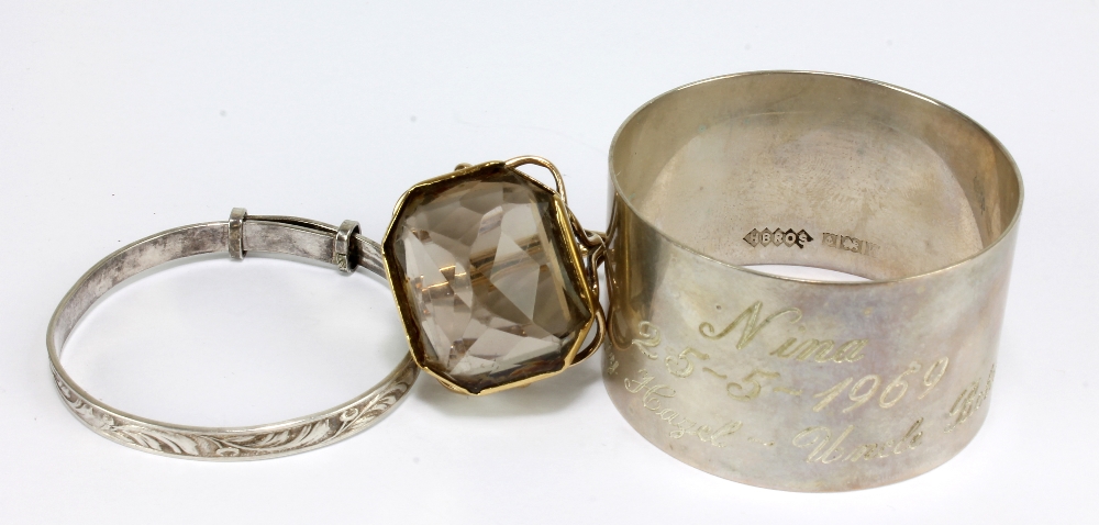 A hallmarked silver napkin ring with presentation inscription, a child's silver bangle, and a 9ct