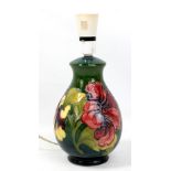 MOORCROFT; a 'Hibiscus' pattern tubeline decorated lamp base on green ground with impressed marks to