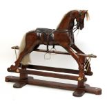 An early 20th century stained pine rocking horse with horse hair mane and tail, leather tack and