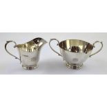 A George V hallmarked silver sucrier and creamer with monogram to the front,