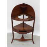 An Edwardian mahogany corner washstand with space for wash bowl and glasses with lower shelf,