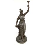 A contemporary bronzed life sized figure of a classical maiden holding a torch aloft and wearing