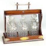 A 1920s oak and silver plate mounted three bottle tantalus, with key and bottle labels to