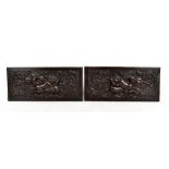 A pair of early 19th century carved oak rectangular panels, each decorated with a cherub blowing a