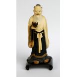 A good Japanese Meiji period carved and stained ivory okimono of a bearded gentleman holding a