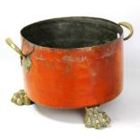 A 19th century copper circular pot with brass carrying handles and three brass paw feet, engraved