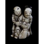 A Japanese Meiji period carved ivory netsuke of two figures beside a sack, height 4.5cm.