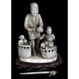 A Japanese Meiji period sectional Okimono of a fruit seller and boy, with associated wooden