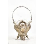 A German embossed and pierced swing handled silver basket with shaped clear glass liner,