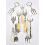 A group of nine electroplated bread forks some with mother of pearl handles, silver sheath