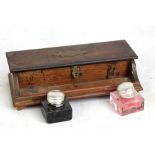 A teak pen and ink stand, inlaid with brass corners and cartouche, with two glass inkwells, length