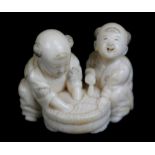 A Japanese Meiji period carved ivory netsuke of two figures washing, signed to base, length 4cm.