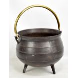 A cast iron cauldron with brass swing handle raised on tripod, feet diameter 36cm.