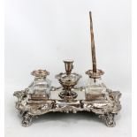 A Victorian silver plated foliate motif ink stand with twin clear glass inkwells raised on four