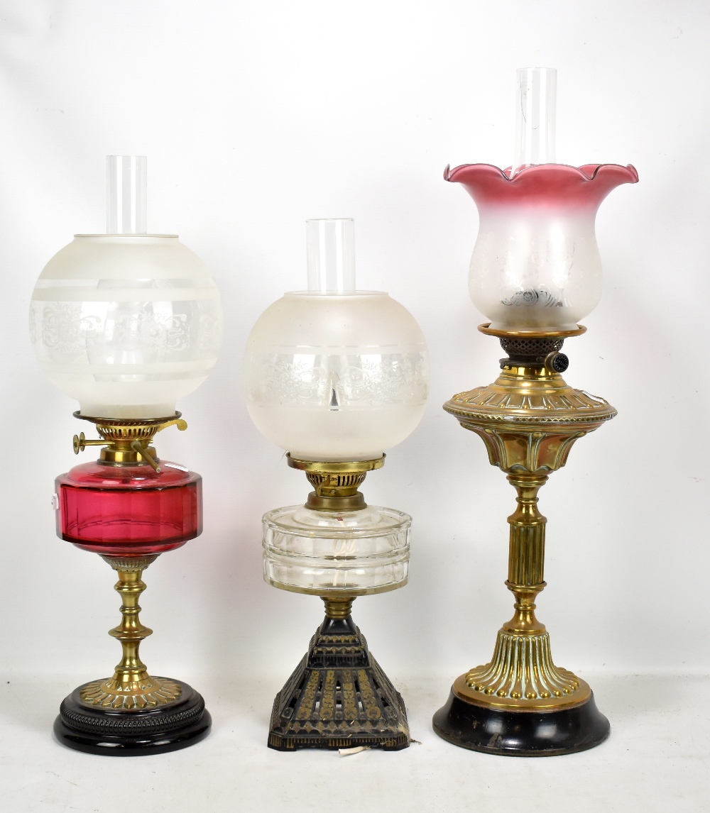 A Victorian brass oil lamp with pink tinted etched shade, a further oil lamp with cranberry