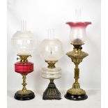 A Victorian brass oil lamp with pink tinted etched shade, a further oil lamp with cranberry