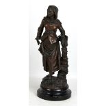 A late 19th century spelter figure of a young woman holding a basket, set on ebonised circular