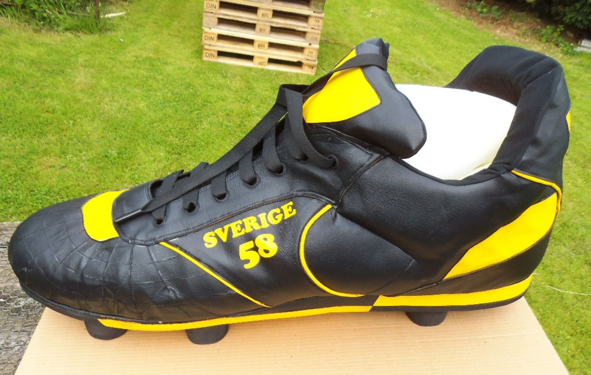 A pair of giant sized black and yellow football boots, length 100cm.