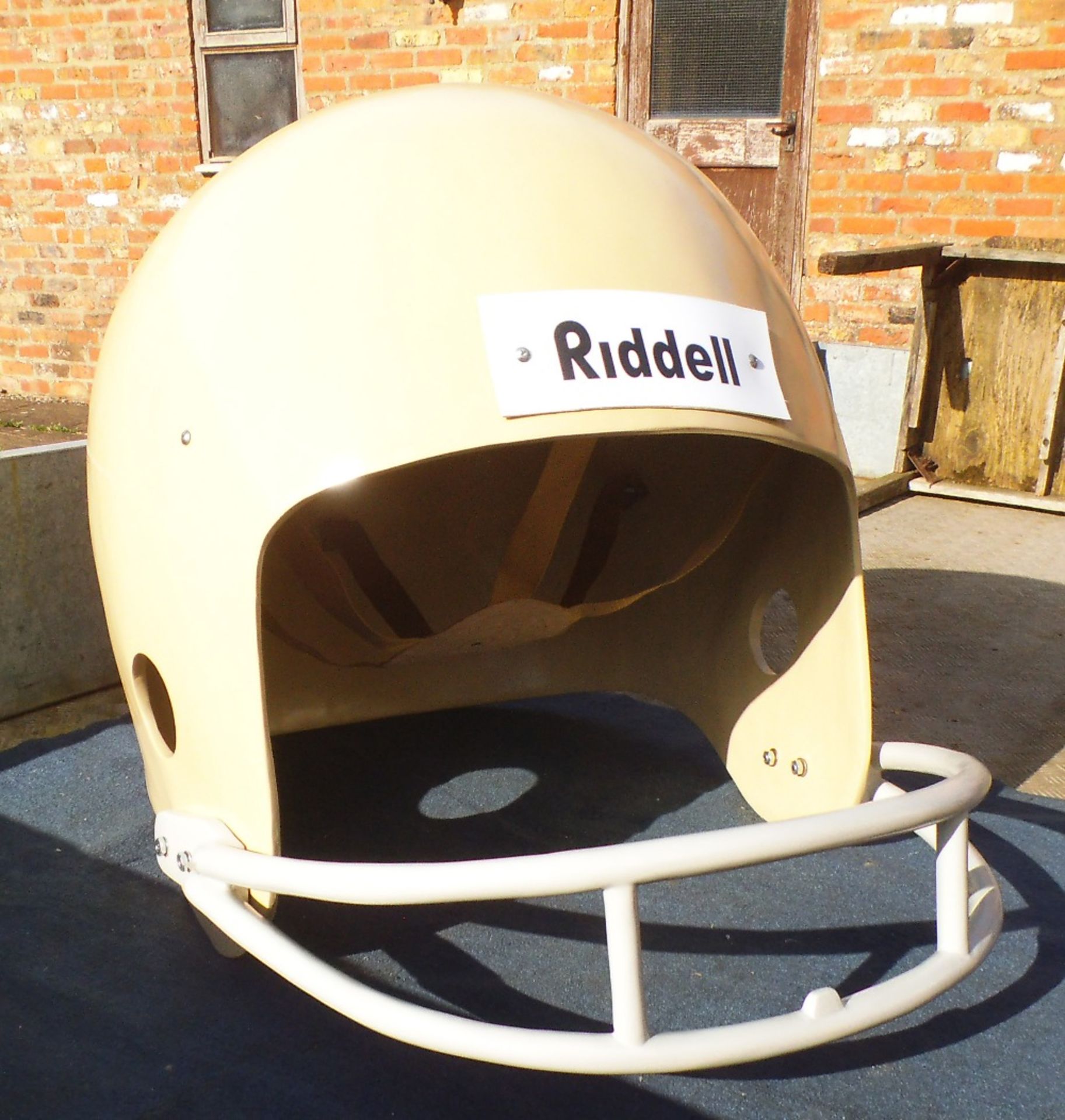 A giant oversized cream fibreglass American football helmet, 100 x 95 x 85cm.