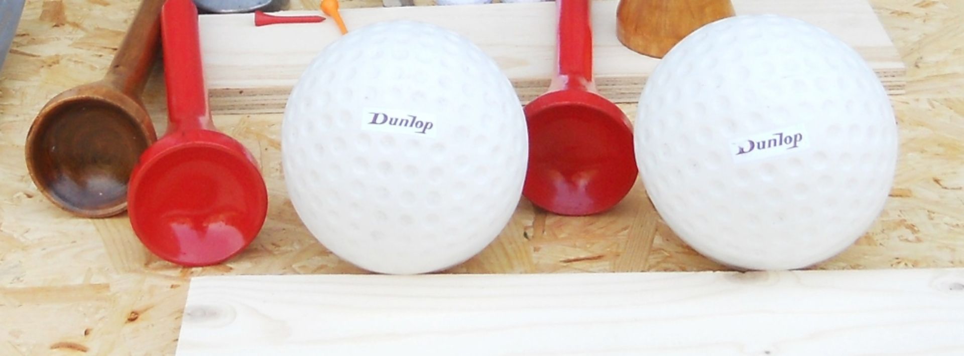 Five giant golf balls (diameter 13cm) and five wooden tees, length 30cm.