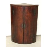 A George III mahogany bow-front corner cupboard with three interior shelves, length 96cm.