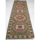 A Persian green ground runner with abstract medallion decoration, approx 80 x 283cm.