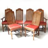 A set of six walnut dining chairs with caned backs and overstuffed seats (4 + 2).