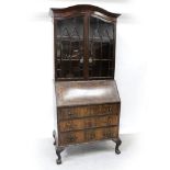An early/mid-20th century walnut elevated bureau bookcase with arched top and astragal glazed doors