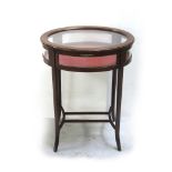 An Edwardian mahogany inlaid bijouterie, oval glass top and glass panels to the sides,