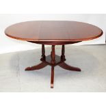 A red stained circular teak extending dining table with faux leather central leaf,