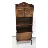 A c1930s oak slender bookcase, two small cupboard doors over one shelf and lower magazine rack,