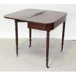 A George III mahogany fold-over tea table supported on turned and reeded legs to brass castors,