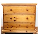 A modern pine chest of three drawers, raised on bun feet, height 73cm.