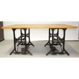 A large rectangular dining table on two cast metal Singer treadle sewing machine supports,