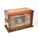 An oak stationery cabinet with glazed fall front enclosing twin inkwells and three drawers, twin