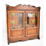 An oak smoker's cabinet with twin glazed doors with pipe racks and arrangement of four small drawers