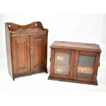 Two oak smoker's cabinets, the smaller example with twin glazed doors and twin handles, both with