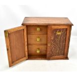 An Art Nouveau oak and stencil decorated smokers cabinet with three internal drawers, width 39cm.