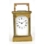 A circa 1900 French brass carriage clock with white enamel dial set with Roman numerals and numbered