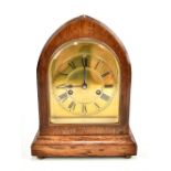 An early 20th century oak lancet shaped mantel clock with brass dial set with Roman numerals, height