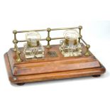 An Edwardian oak ink standish with raised brass three quarter gallery, twin substantial cut glass