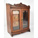 An oak smoker's cabinet with twin glazed doors enclosing arrangement of three small drawers, 47 x