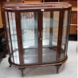 A sapele mahogany bow-front display cabinet with adjustable glass shelves over short cabriole legs,