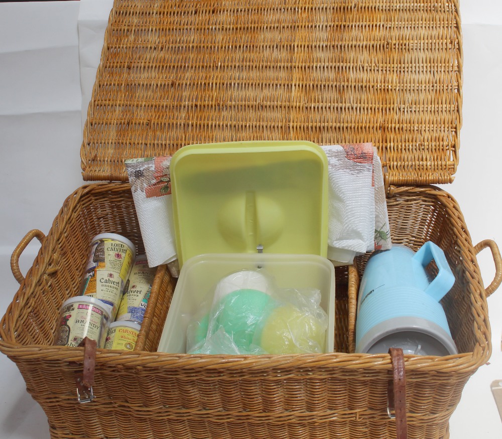 A vintage c1960s picnic basket with four advertising beakers, plastic tablecloth,